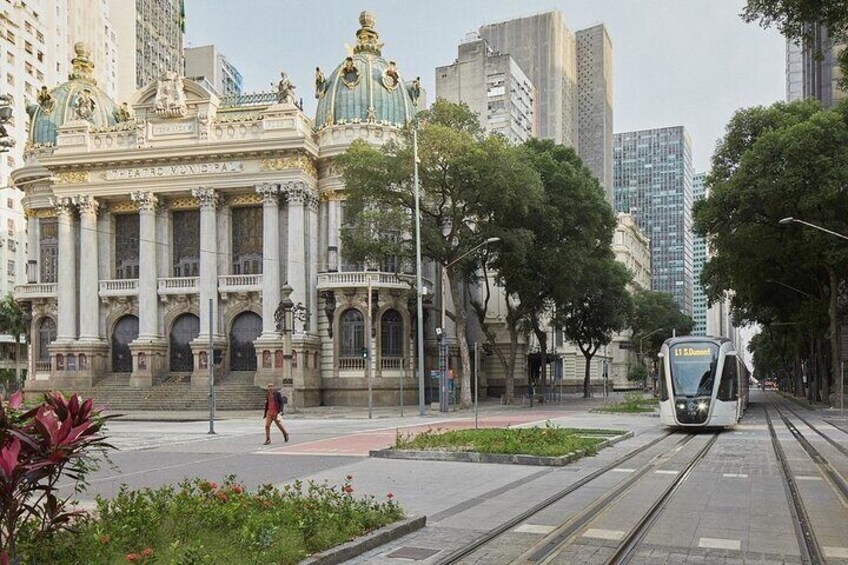 A tram on tracks, a grand building with domes, and a pedestrian crossing. 1