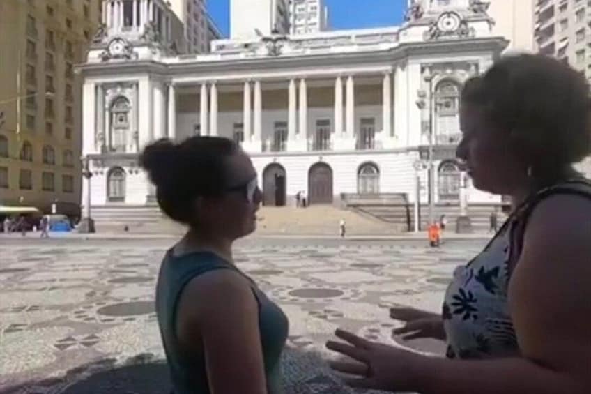 Two people conversing in front of a large classical building with columns and steps. 2