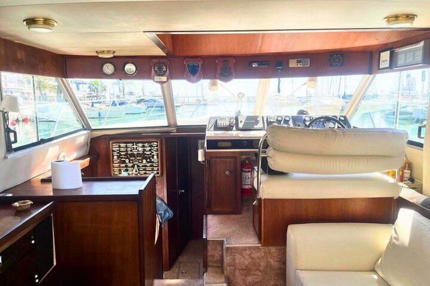 A boat's interior with a steering wheel, control panel, and seating area. 4