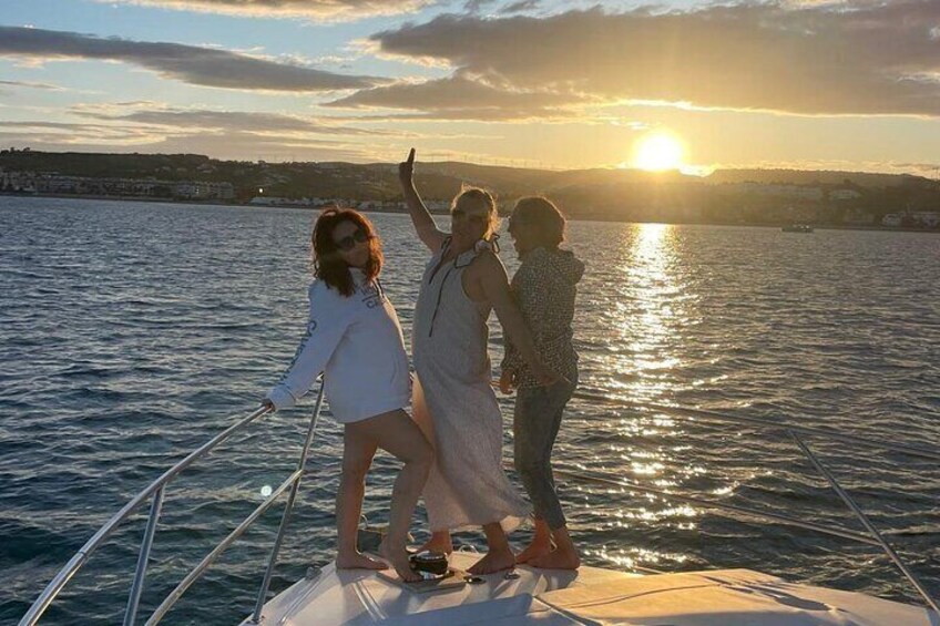 Three people on a boat with the sun setting in the background. 1