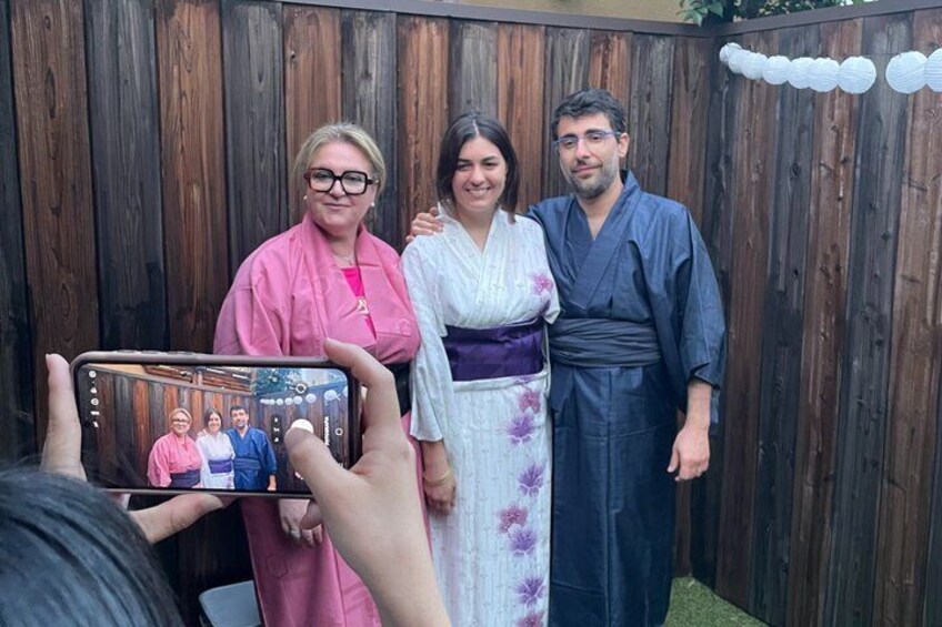 A group of people in traditional attire standing in front of a wooden fence. 2