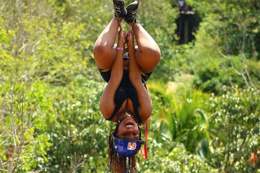 A person upside down, suspended in a natural setting with dense greenery. 3