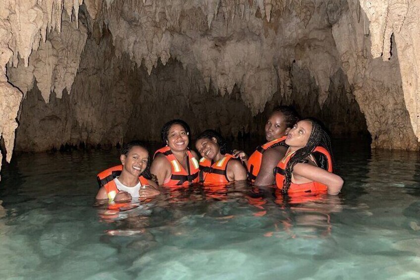 A group of people in a cave with water, wearing life jackets. 2