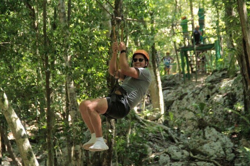 A person zip-lining through a forested area with trees and rocky terrain. 3