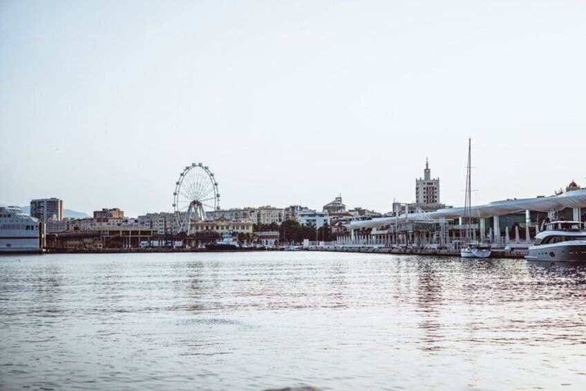 A waterfront cityscape with a prominent Ferris wheel, a marina with yachts, and a distinctive building with a spire. 2