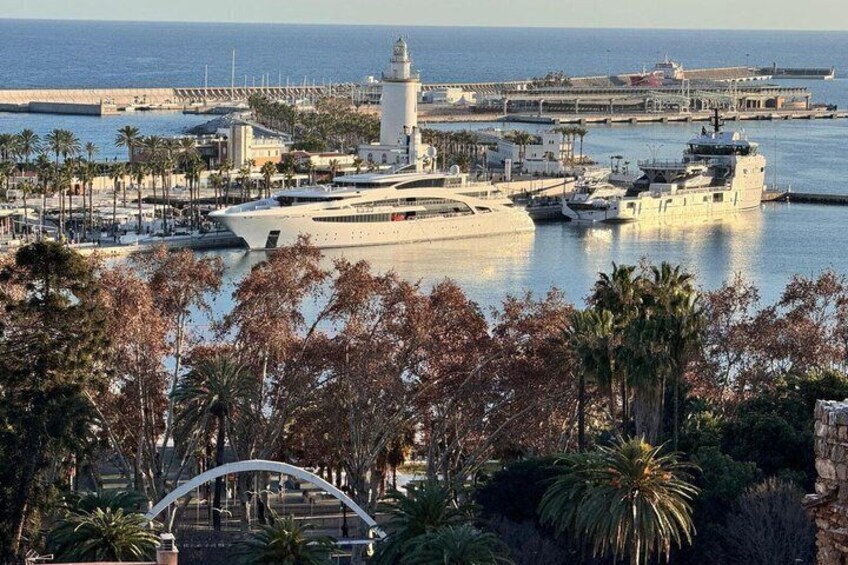 A coastal marina with yachts, a lighthouse, and a promenade lined with palm trees. 3