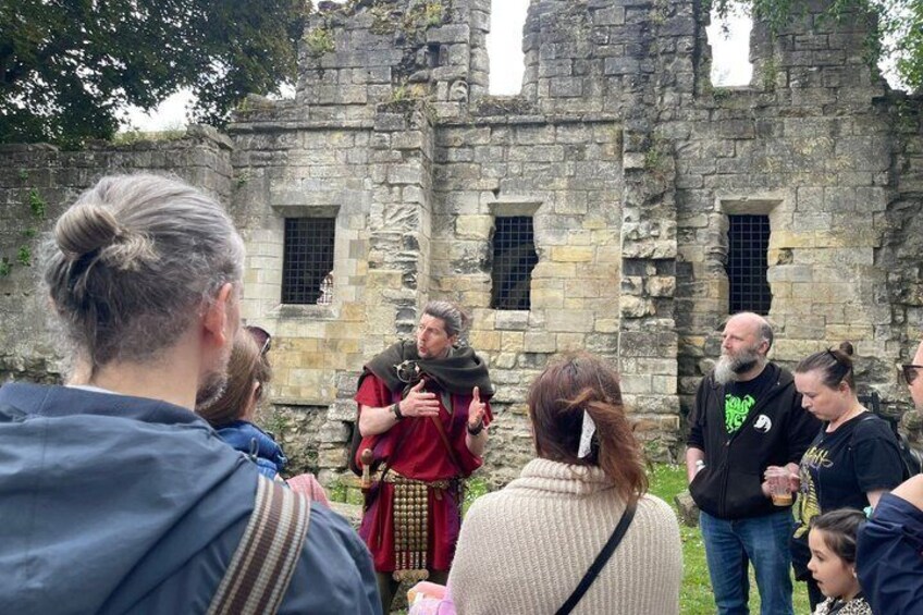 A group of people in front of a historical stone building with arched windows. 1