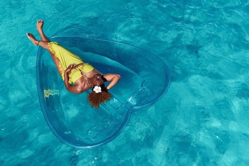A person floating in a clear blue pool wearing a yellow swimsuit. 4