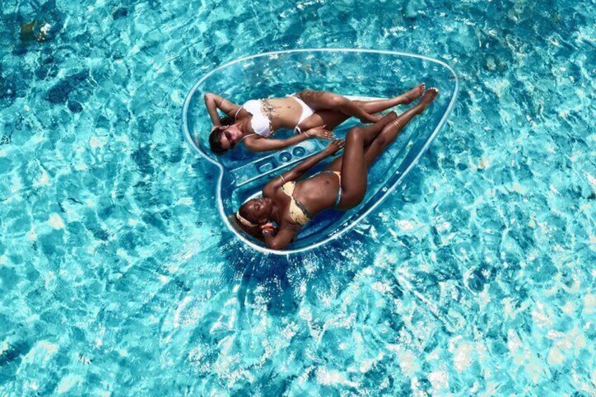 Two people floating on an inflatable heart-shaped object in a pool. 2