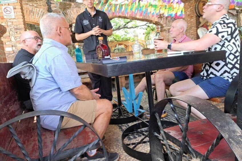 A group of people seated around a table with a bartender standing behind. 3