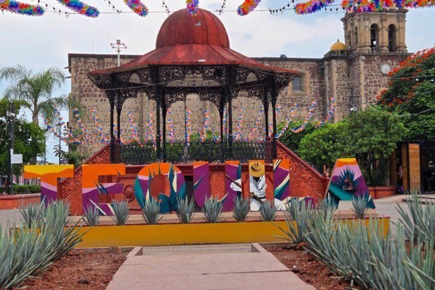 A colorful outdoor sculpture with a gazebo in front of a historic building. 1