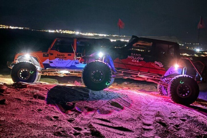 A 4x4 vehicle with 'SAND HOLLOW' branding on a sandy terrain at night. 1