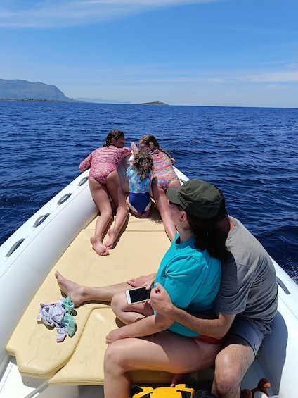 A boat with three people wearing swimsuits, a man holding a phone, and a child with a stuffed toy. 5