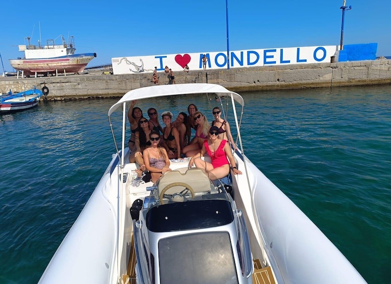 A group of people on a boat with a sign in the background that says 'I ♥ MONDELLO'. 1