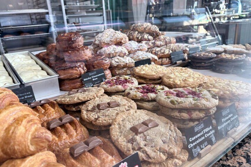 A bakery display with various pastries and cookies, including croissants and chocolate chip cookies. 4