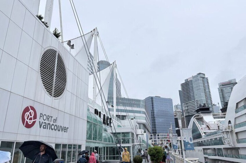 A modern building labeled 'Port of Vancouver' with a distinctive circular window and a bridge structure in the background. 1