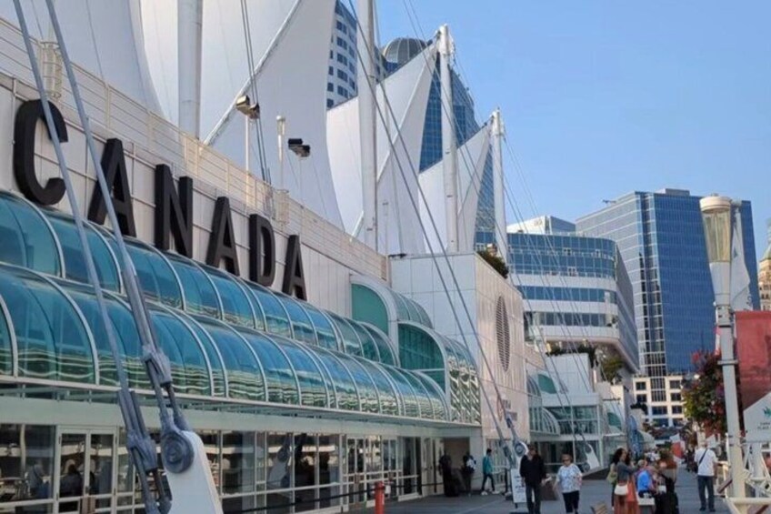 A large building with 'CANADA' written on it, surrounded by modern architecture. 1