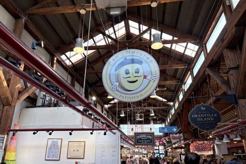 A market with a circular sign featuring a smiling chef, wooden beams, and various shops. 2