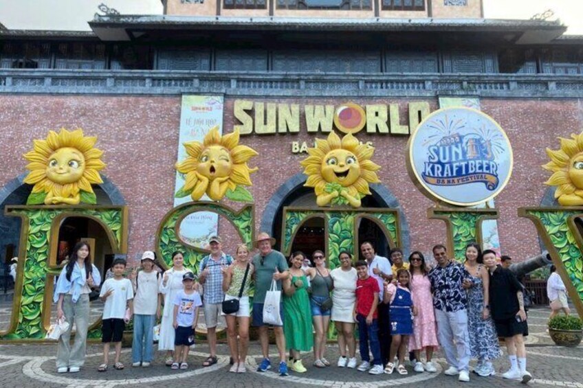 A group of people in front of a building with sun motifs and a sign for 'SUN WORLD' and 'SUN KRAFTBEER.' 2