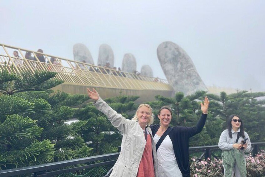 Three people standing on a bridge with a large rock formation in the background. 5