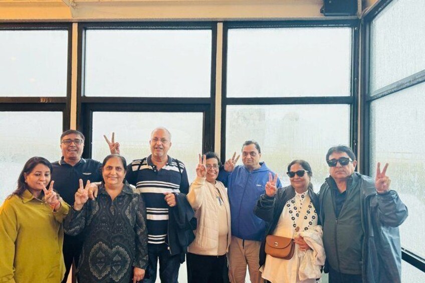 A group of people posing in front of a building with large windows. 3