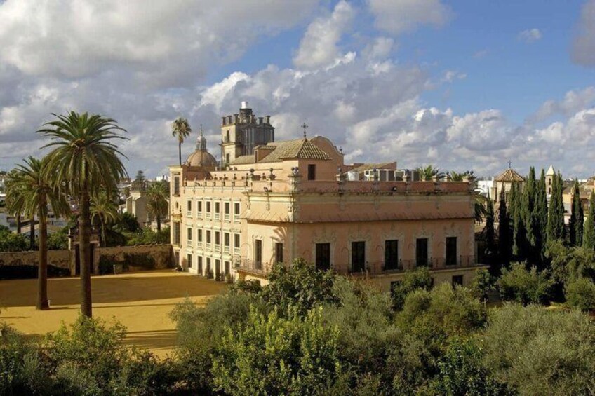 A historic building with domed architecture, surrounded by greenery and palm trees. 2
