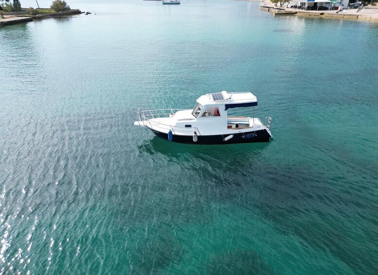 A white boat with a cabin and a canopy, floating on calm turquoise water. 5