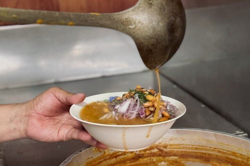 A hand holding a bowl with a sauce being poured over it. 4