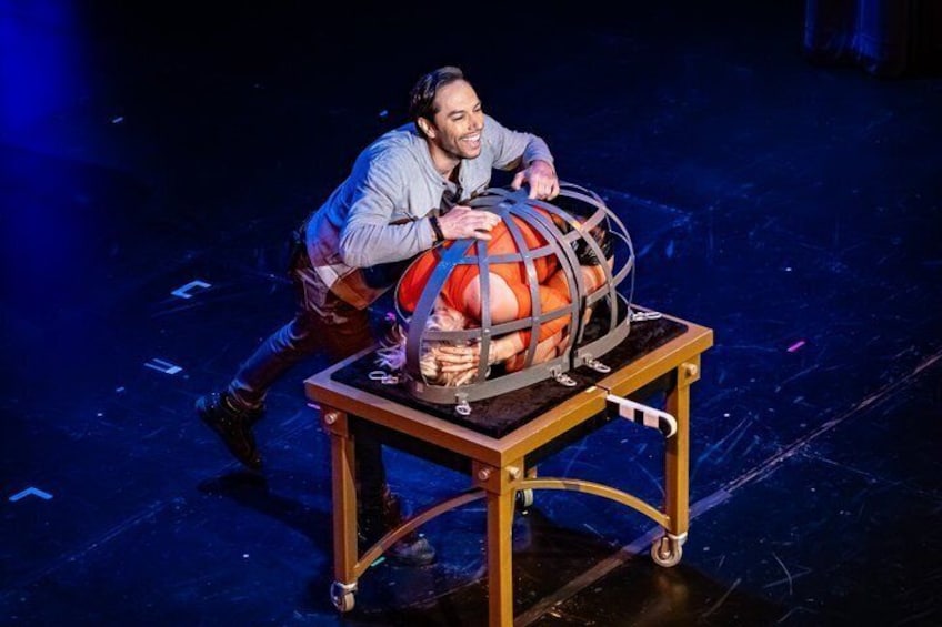 A person on stage with a large spherical object on a table. 4