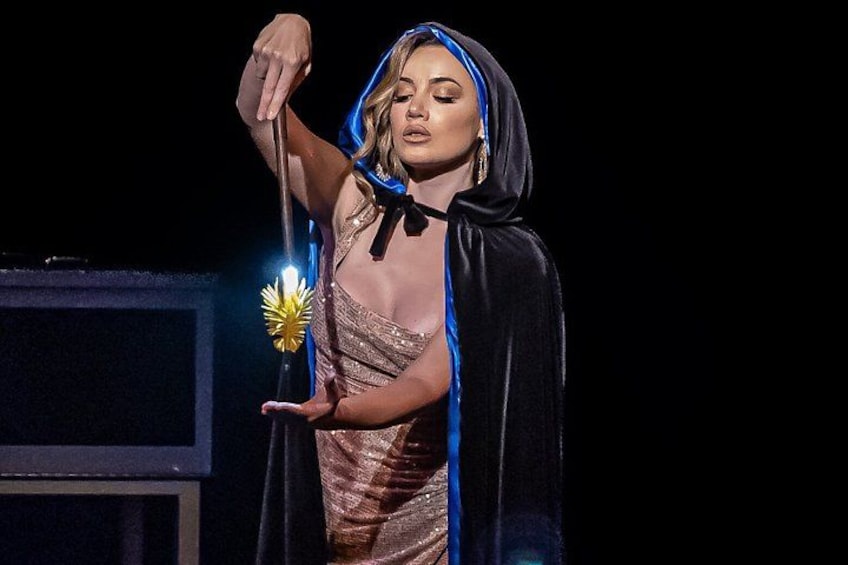 A person in a hooded outfit holding a wand. 3