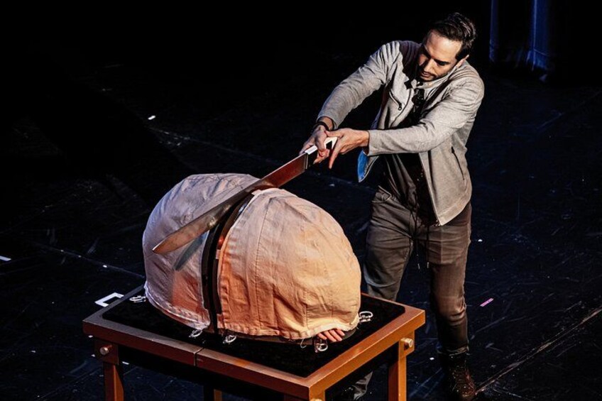 A person handling a large, covered object on a table. 2