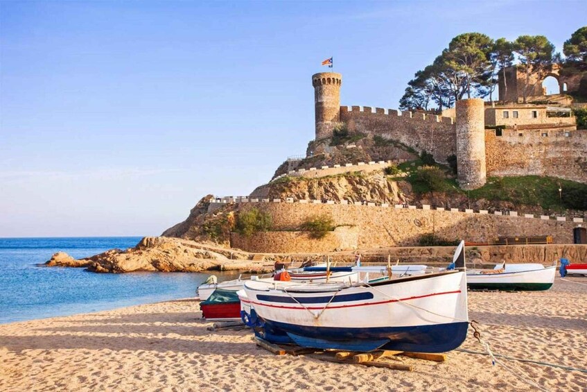 A coastal fortification with a tower, boats on the beach, and clear skies. 1