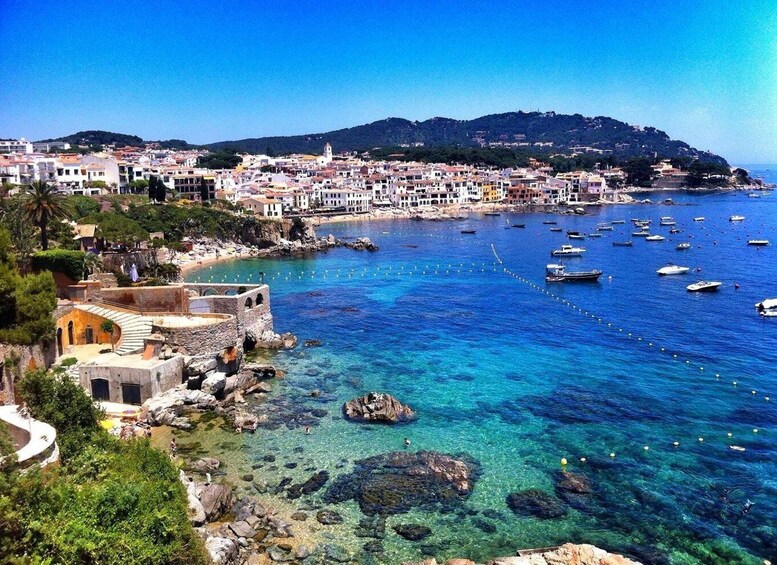 A coastal town with clear blue waters, boats, and historic buildings. 3