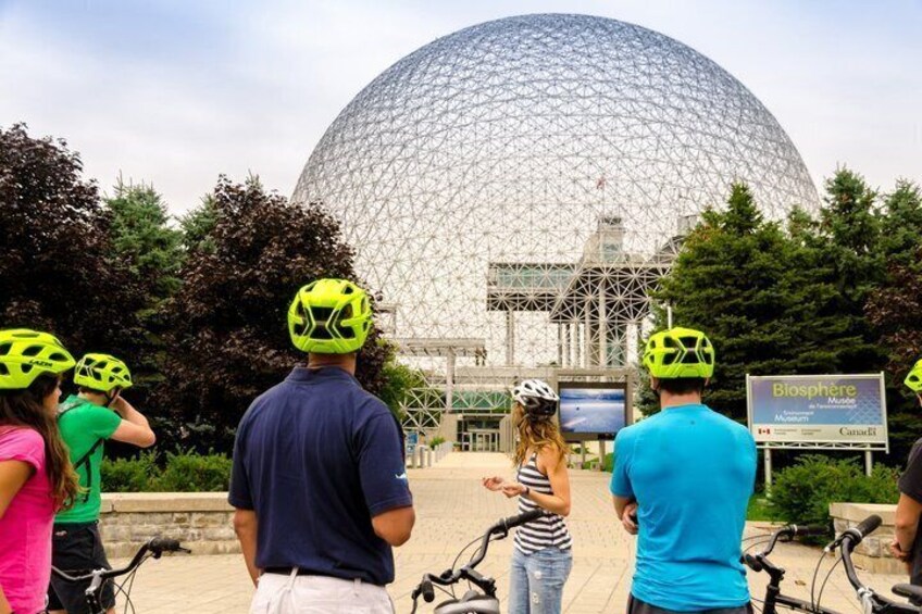 People with bicycles and helmets in front of a large geodesic dome structure. 3