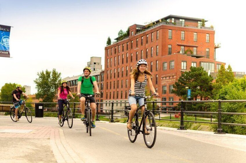 Cyclists on a paved path with a red brick building in the background. 5