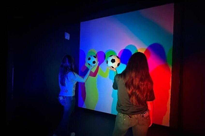 Two people interacting with a colorful projection on a wall. 5
