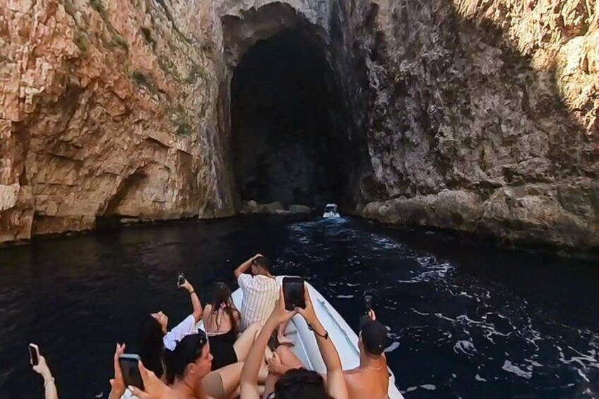 A group of people on a boat in a rocky waterway with a cave entrance. 1