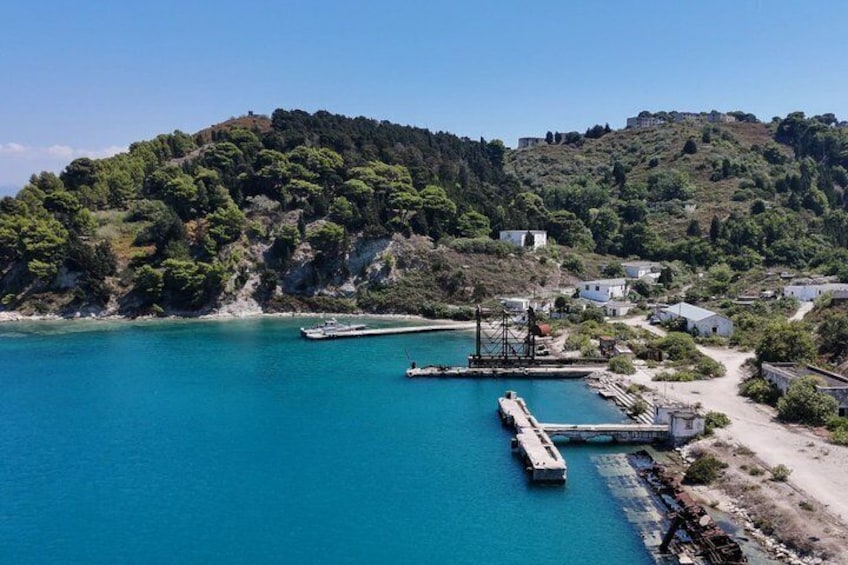 A coastal village with a pier extending into turquoise waters, surrounded by lush hills and traditional buildings. 4