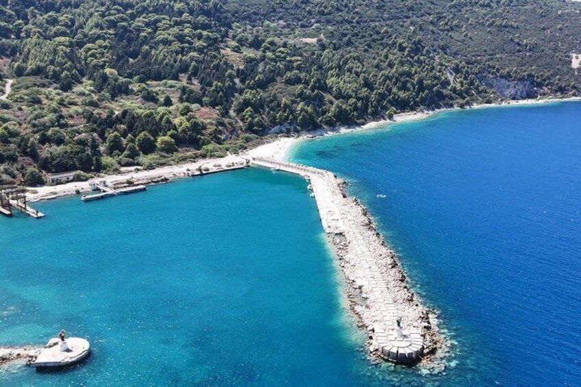 A coastal area with a pier extending into turquoise waters, surrounded by dense forest. 3