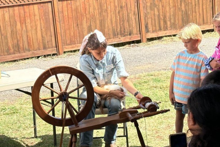 A person spinning a wheel with a child and another person nearby. 2