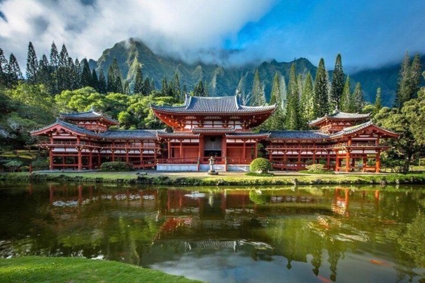 A traditional Japanese temple with a pond in front, surrounded by lush greenery and mountains. 2