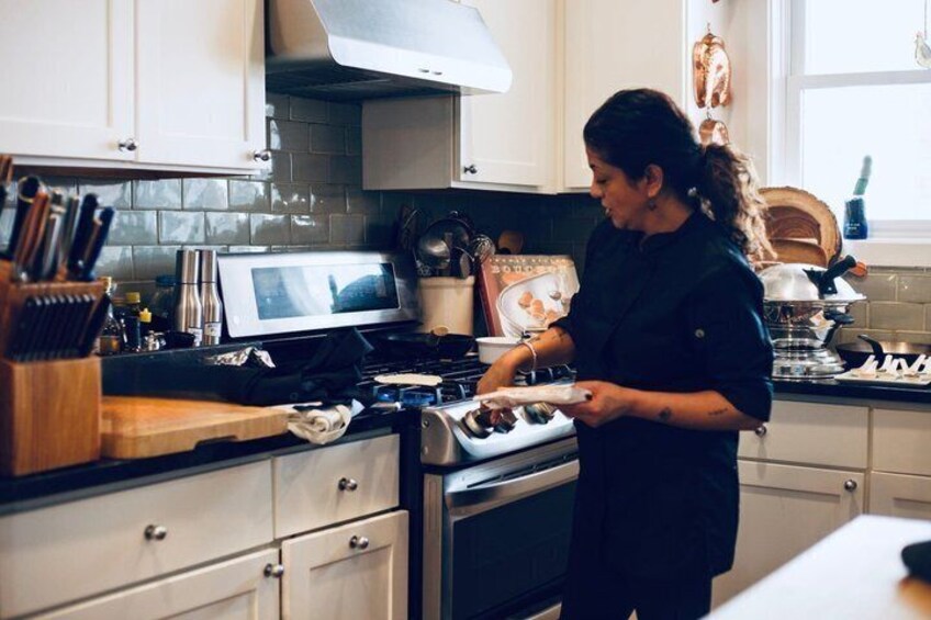 A person cooking in a kitchen with a stove, microwave, and various utensils. 3