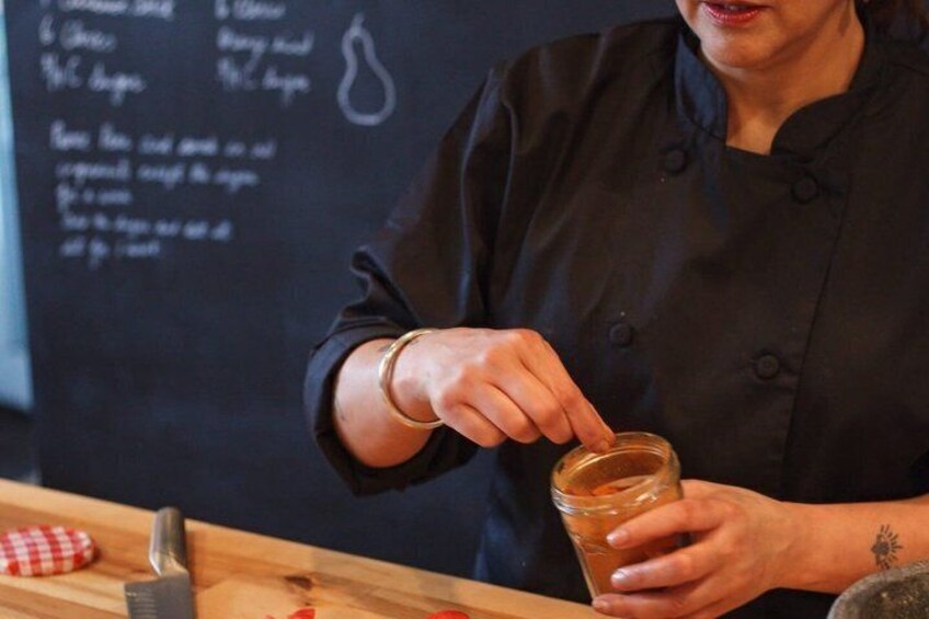 A person in a black chef's coat holding a jar. 2