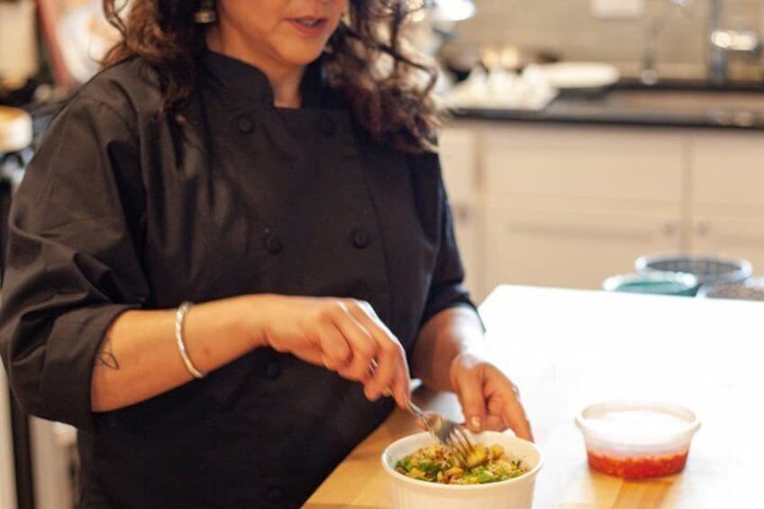 A person in a black chef's coat preparing food at a kitchen counter. 4