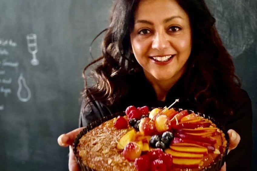 A person holding a fruit-topped cake. 5