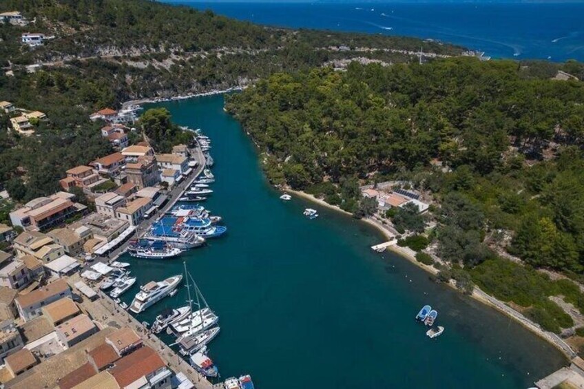 A coastal town with a marina, boats, and a forested hillside. 1