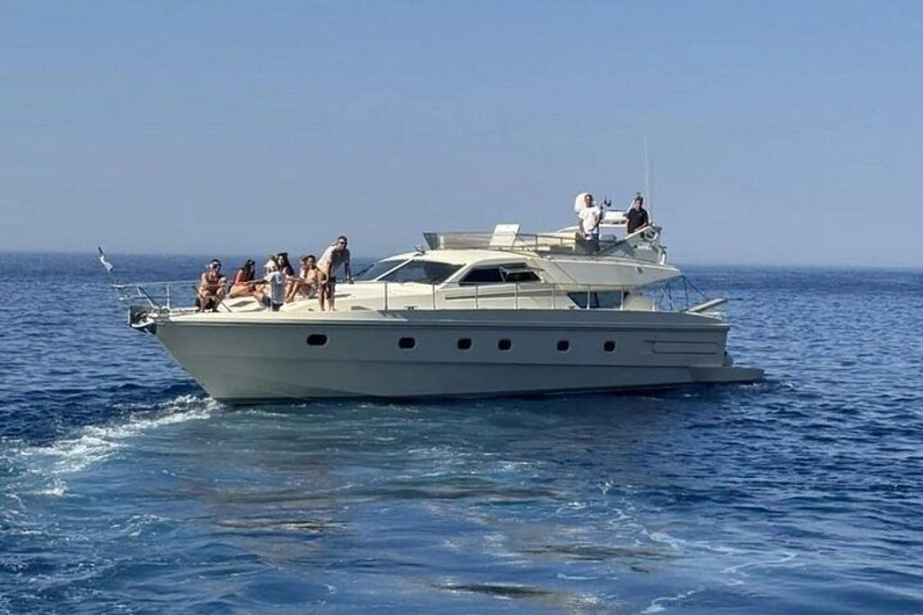 A large yacht with multiple people on deck, sailing on a calm sea. 4