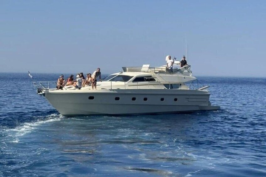 A large yacht with multiple people on deck, sailing on open water. 4