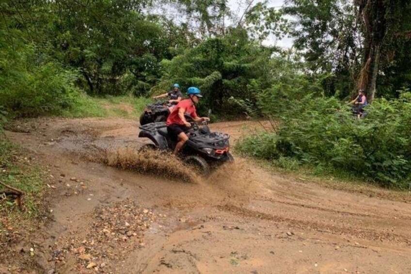 A group of people on an ATV navigating a muddy off-road trail in a forested area. 5