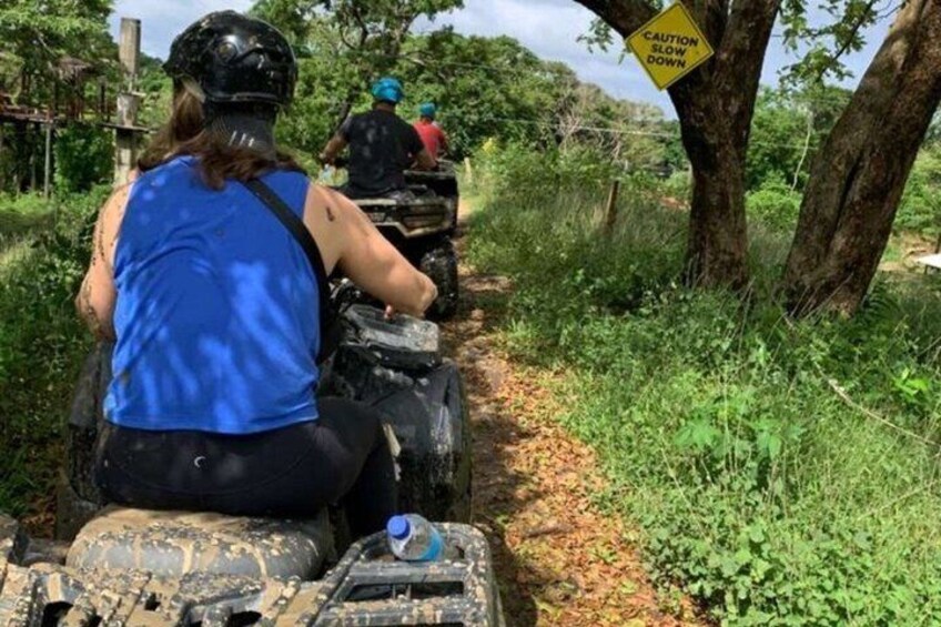 A person riding an ATV on a narrow path with caution signs. 3